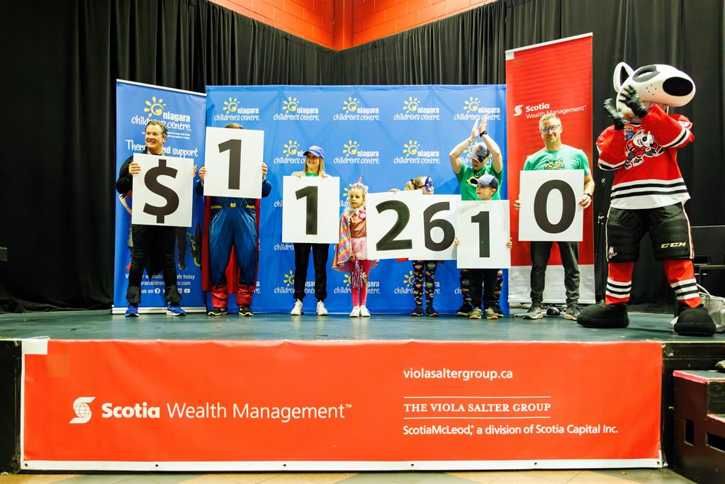 People display $112,610 on white boards on a stage